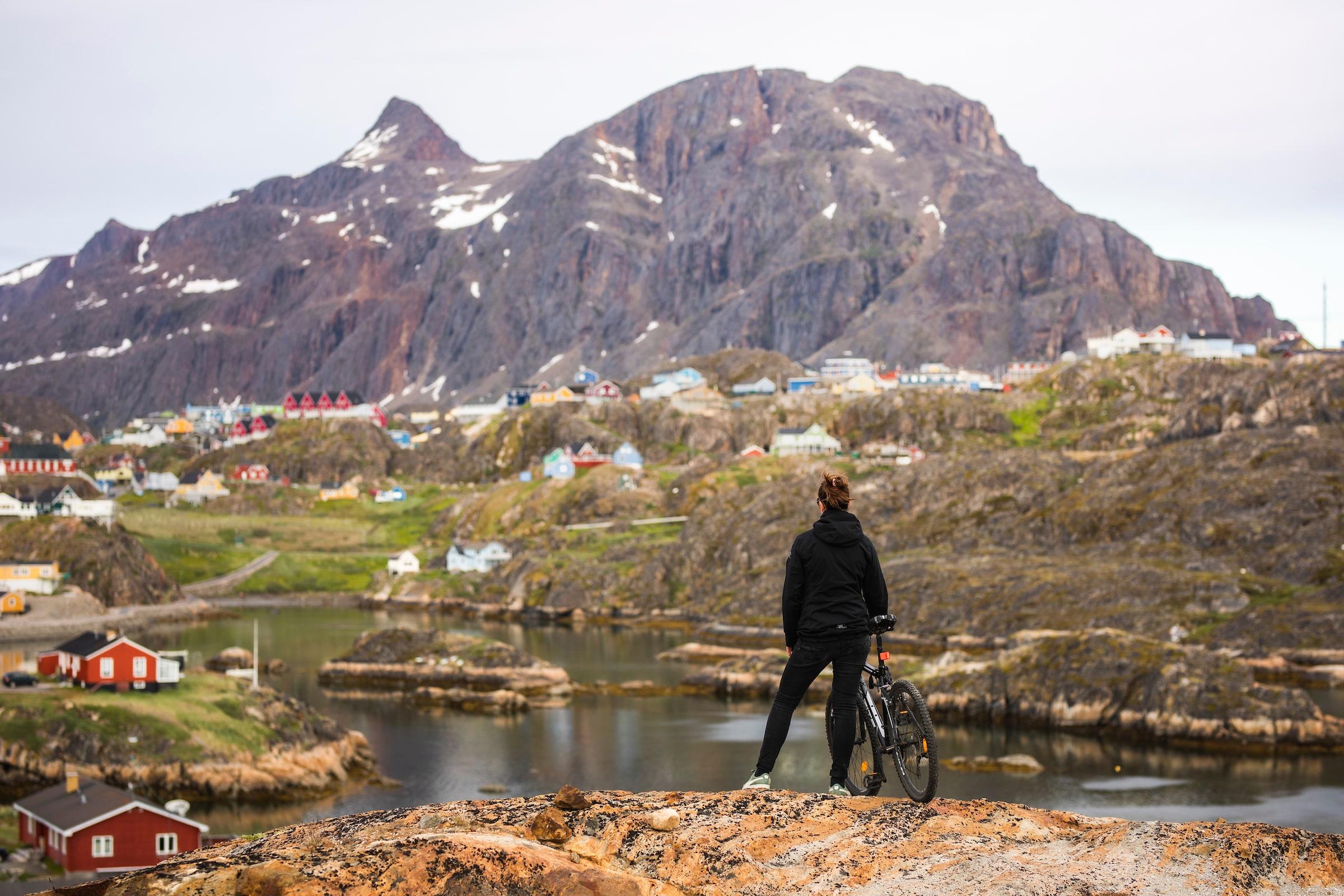 Cyclist in Sisimiut with mountain. Photo - Aningaaq R. Carlsen, Visit Greenland
