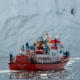 A tour boat in fron of an iceberg wall in the Ilulissat Icefjord in Greenland